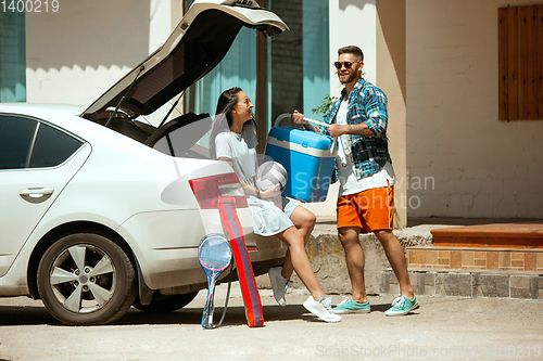 Image of Young couple preparing for vacation trip on the car in sunny day