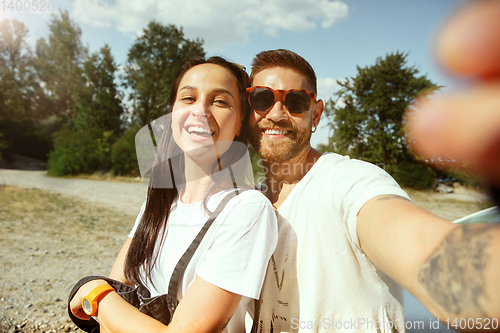 Image of Young couple making selfie near by car in sunny day