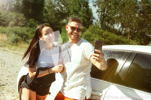 Image of Young couple making selfie near by car in sunny day