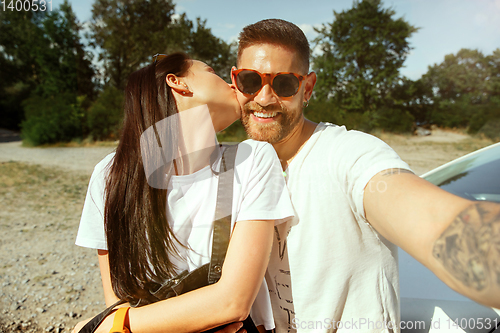 Image of Young couple making selfie near by car in sunny day