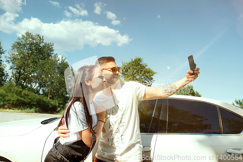 Image of Young couple making selfie near by car in sunny day