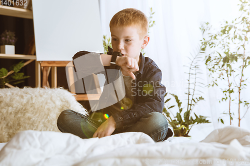 Image of Little boy using different gadgets at home