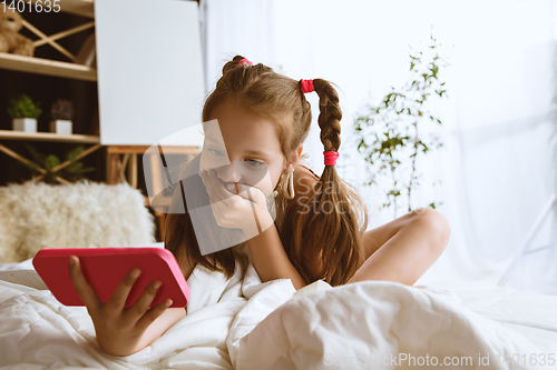 Image of Little girl using different gadgets at home