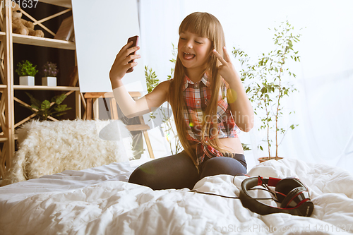 Image of Little girl using different gadgets at home