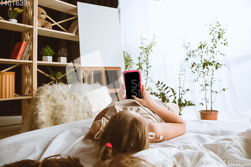 Image of Little girl using different gadgets at home