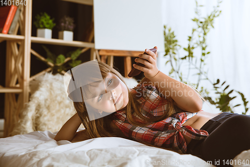 Image of Little girl using different gadgets at home