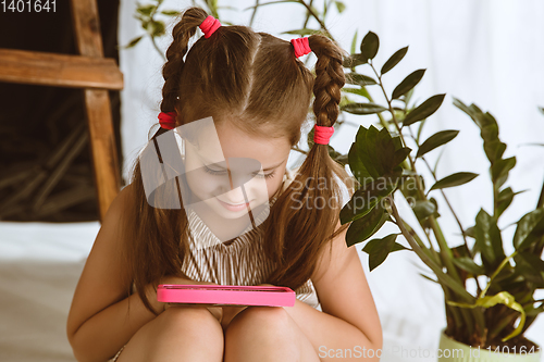 Image of Little girl using different gadgets at home