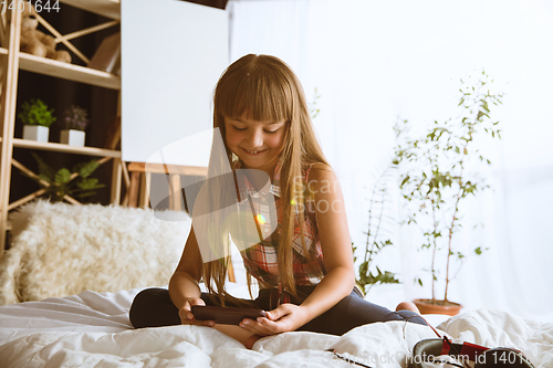 Image of Little girl using different gadgets at home