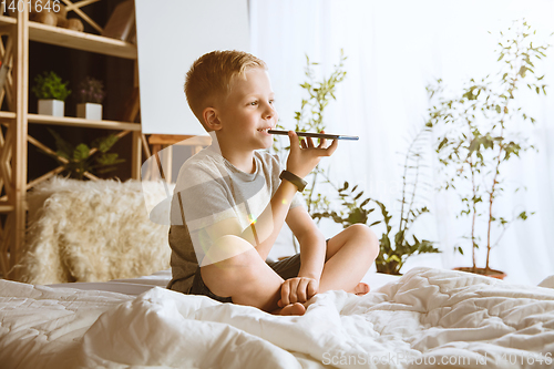 Image of Little boy using different gadgets at home