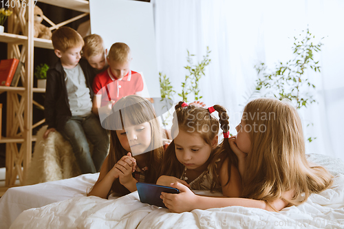 Image of Little boys and girls using different gadgets at home