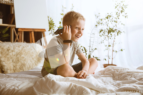 Image of Little boy using different gadgets at home