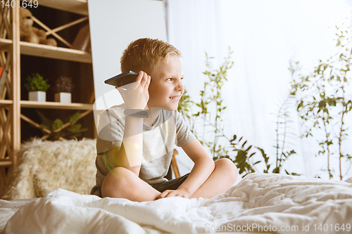 Image of Little boy using different gadgets at home