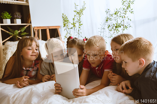 Image of Little boys and girls using different gadgets at home