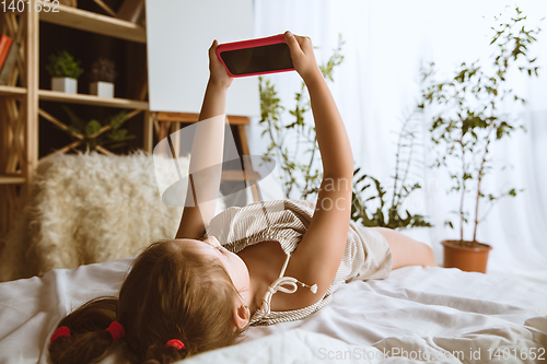 Image of Little girl using different gadgets at home