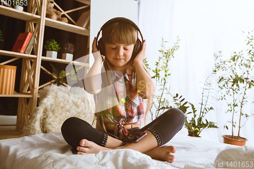 Image of Little girl using different gadgets at home