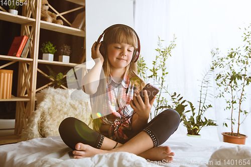 Image of Little girl using different gadgets at home