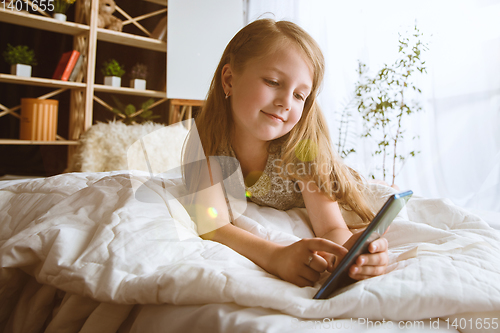 Image of Little girl using different gadgets at home