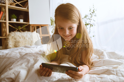 Image of Little girl using different gadgets at home