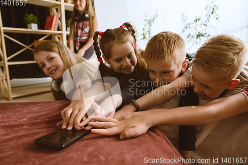 Image of Little boys and girls using different gadgets at home