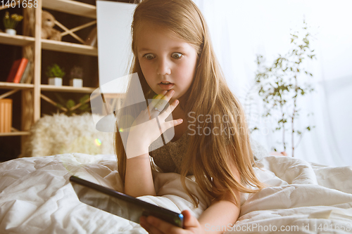 Image of Little girl using different gadgets at home