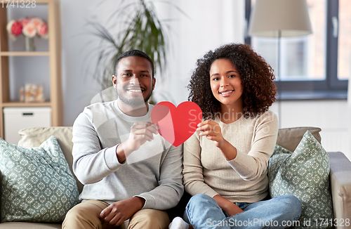 Image of happy african american couple with heart at home