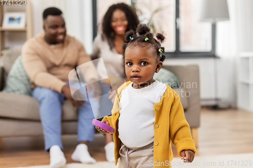 Image of african baby girl playing with toy blocks at home