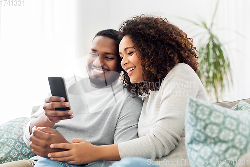 Image of african american couple with smartphone at home