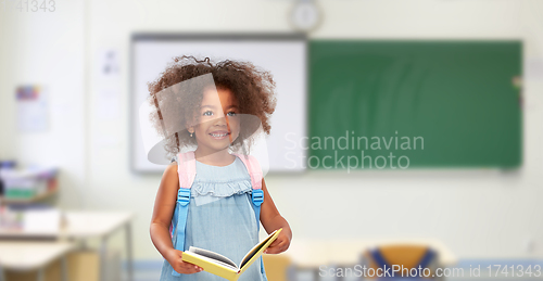 Image of happy little african girl with book and backpack