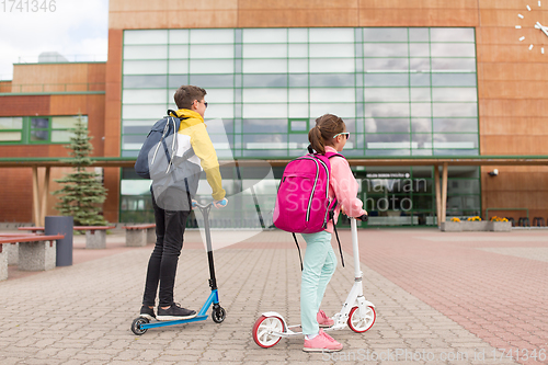 Image of school children with backpacks and scooters