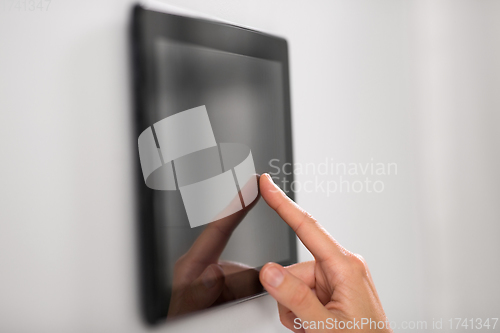 Image of hand using tablet computer at smart home