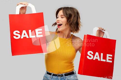 Image of happy young woman with shopping bags on sale