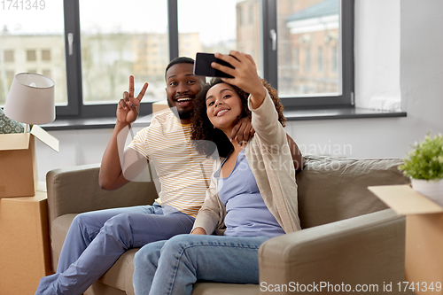 Image of happy couple moving to new home and taking selfie