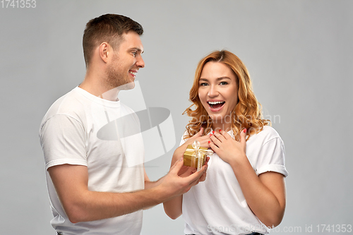 Image of happy couple in white t-shirts with christmas gift