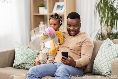 Image of father with smartphone and baby daugter at home
