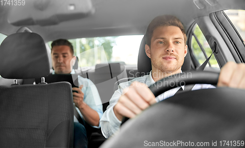 Image of male taxi driver driving car with passenger