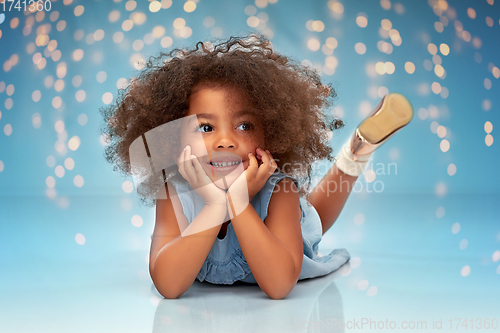 Image of happy little african american girl lying on floor