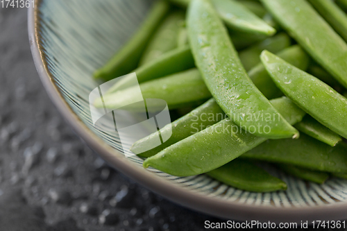 Image of peas in bowl on wet slate stone background