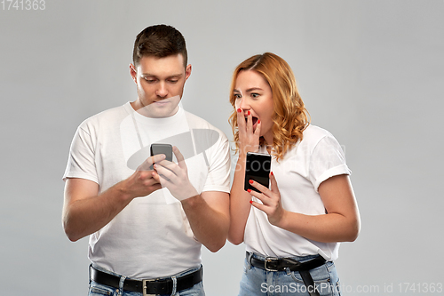 Image of happy couple in white t-shirts with smartphones