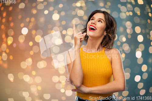 Image of happy smiling young woman pointing finger up