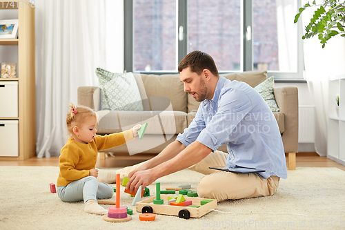 Image of father playing with little baby daughter at home