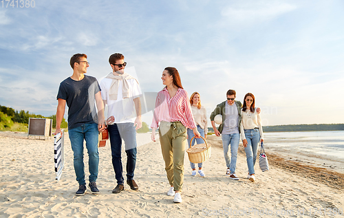 Image of happy friends walking along summer beach