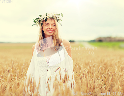 Image of happy young woman in flower wreath on cereal field