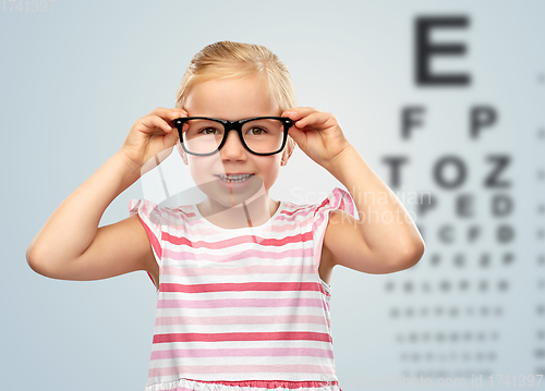 Image of happy little girl in glasses over eye test chart