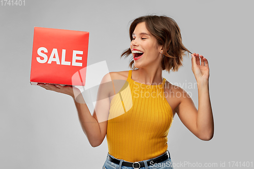 Image of happy smiling young woman posing with sale sign