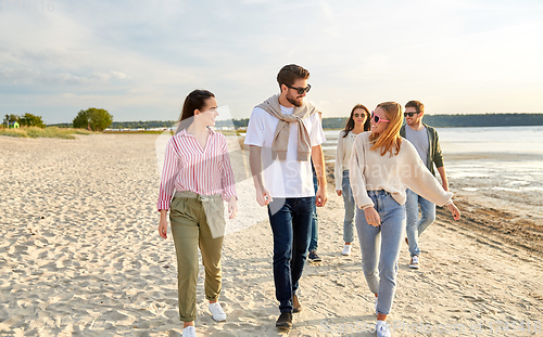 Image of happy friends walking along summer beach