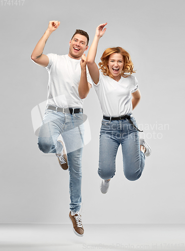 Image of happy couple in white t-shirts jumping