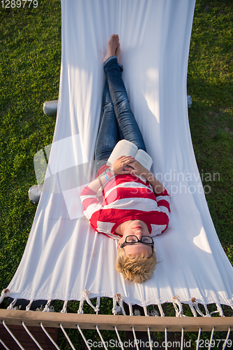 Image of woman reading a book while relaxing on hammock