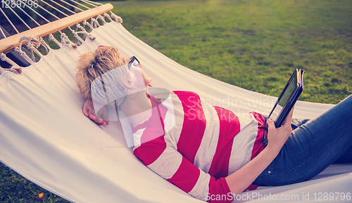 Image of woman using a tablet computer while relaxing on hammock