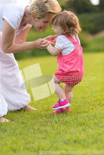 Image of mother and little daughter playing at backyard