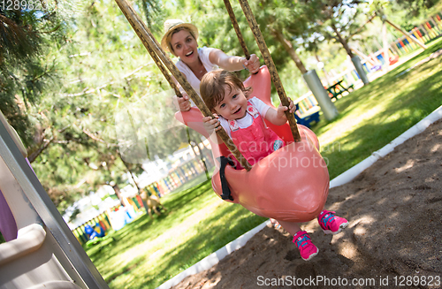 Image of mother and daughter swinging in the park